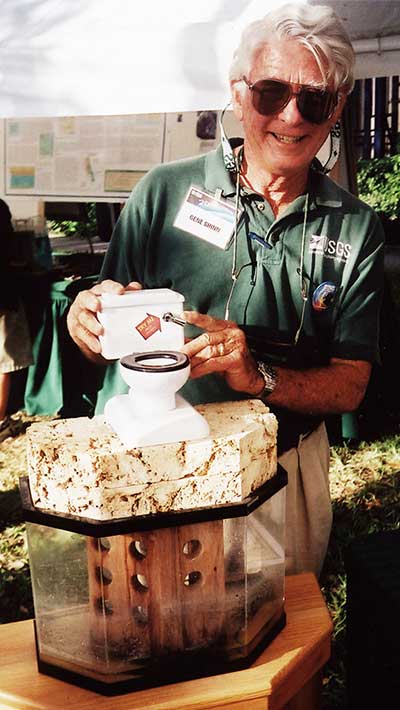 Shinn’s “flushable toilet” demonstrates how sewage flushed or injected into shallow disposal wells flows though porous limestone underlying the Florida Keys, then out to nearby coral reefs. Shinn and his colleagues built this model from a coin bank fitted with a water pump and set on a slab of Key Largo limestone. It has given viewers in a wide range of settings—from school tours and open houses to Congressional briefings—a memorable illustration of limestone permeability.